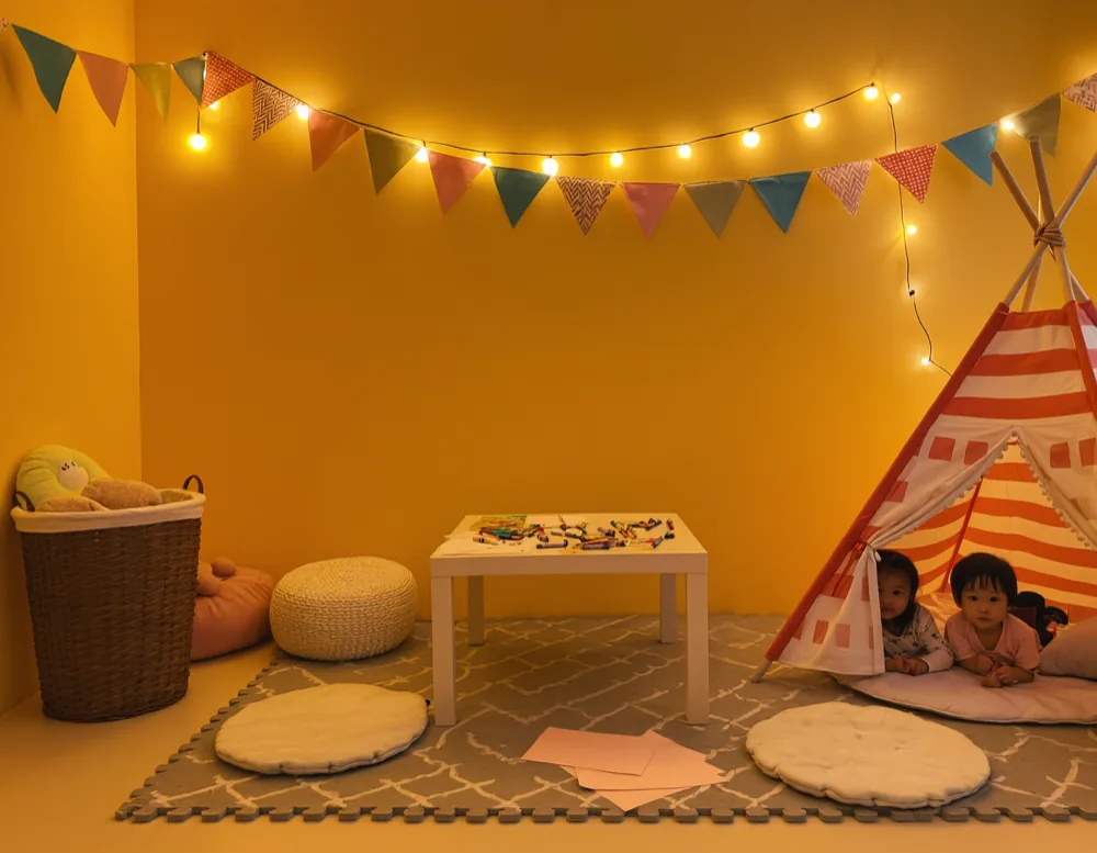 A children's play corner with a mat, pop-up tent and cushions at a family party